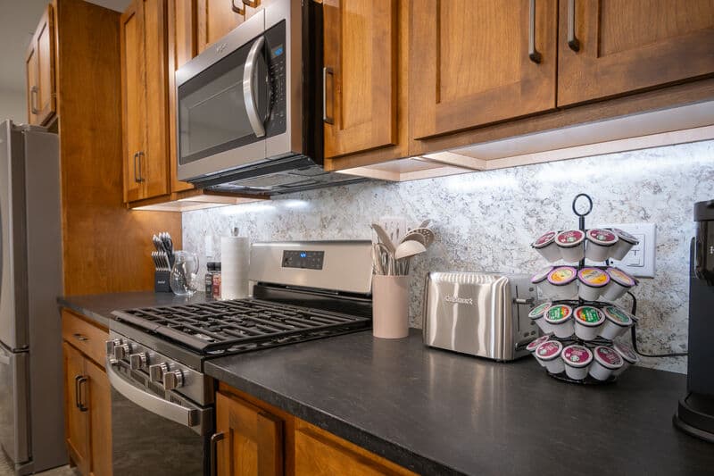 kitchen range with microwave above. black kitchen counters with toaster and individual coffee canisters for automatic coffee machine