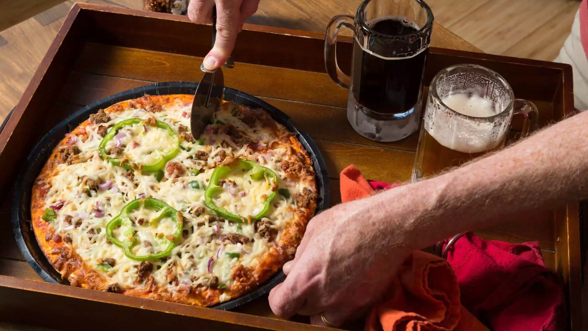 Wooden tray with small veggie pizza and two glasses of beer