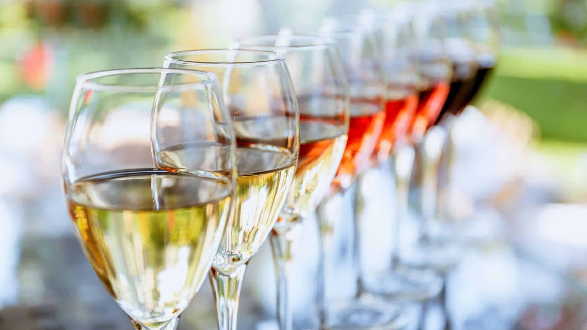 Row of 8 wine glasses filled with varying shades of wine