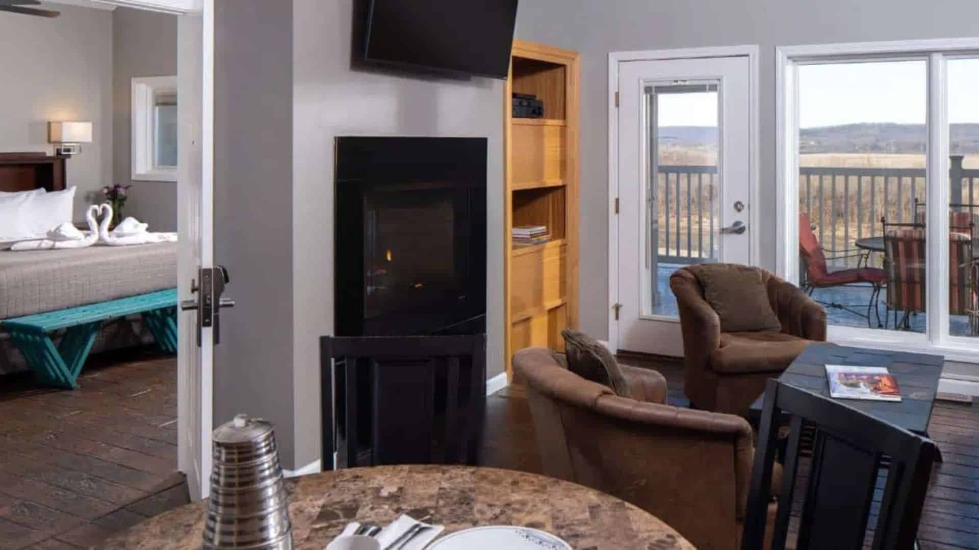 a view of inside one of the river bluff cottages. see into the bedroom, living room with chairs and fireplace, and out onto the deck.