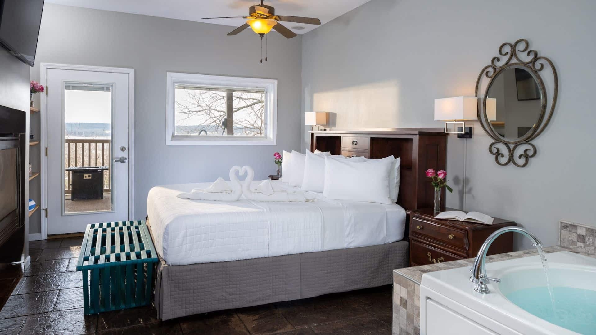 bedroom of the patio-level cottage suite at Hermann Hill including a king size bed with towels folded together to create a heart shape and a tub filling with water