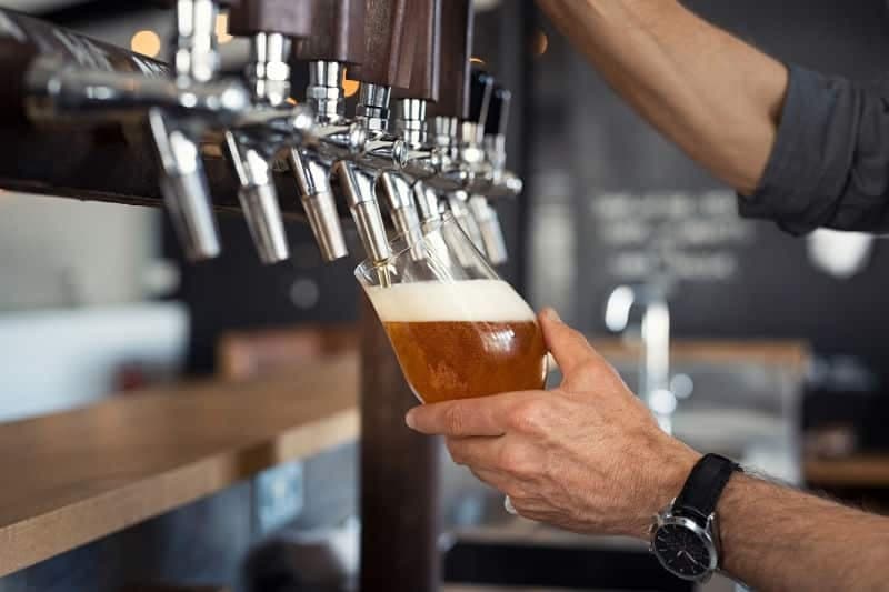 a man filling a glass of beer at a bar