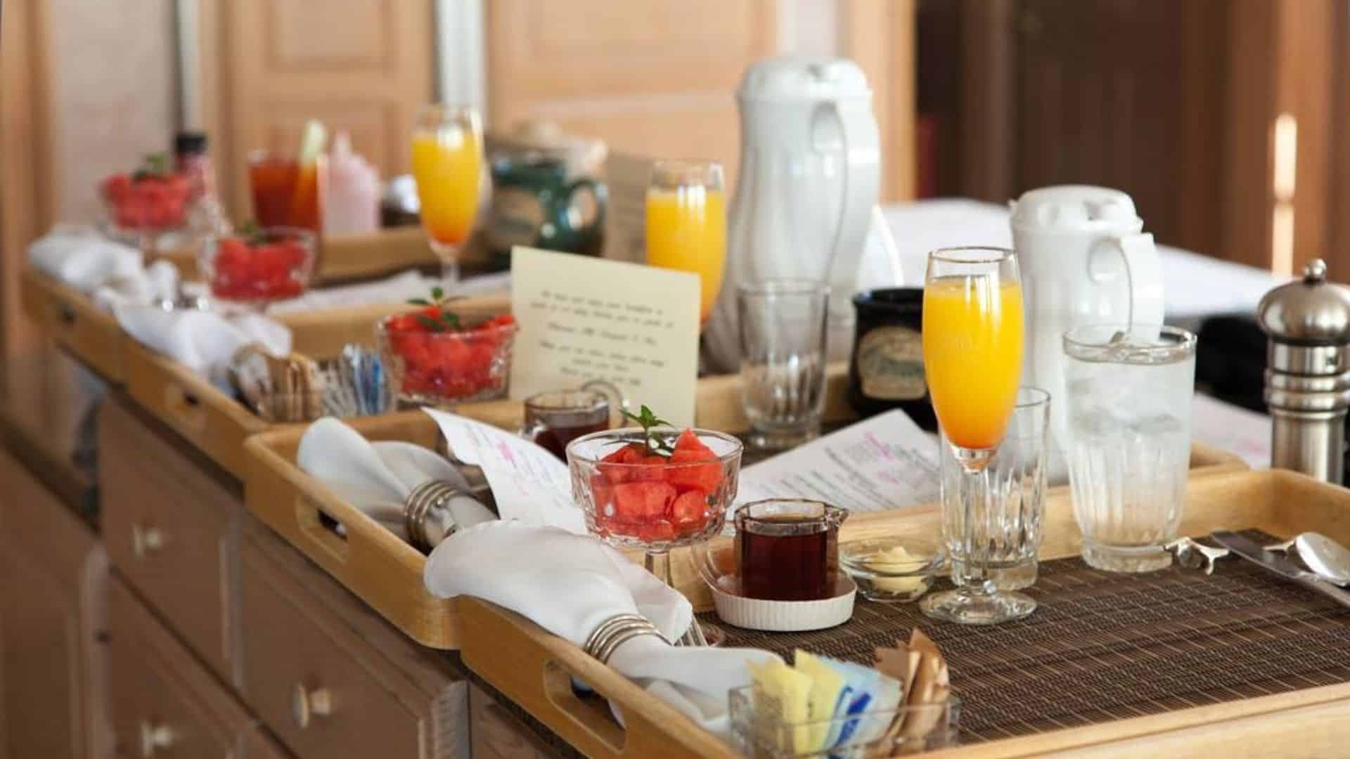 Several wood trays on the counter topped with fresh juice, coffee and fresh fruit