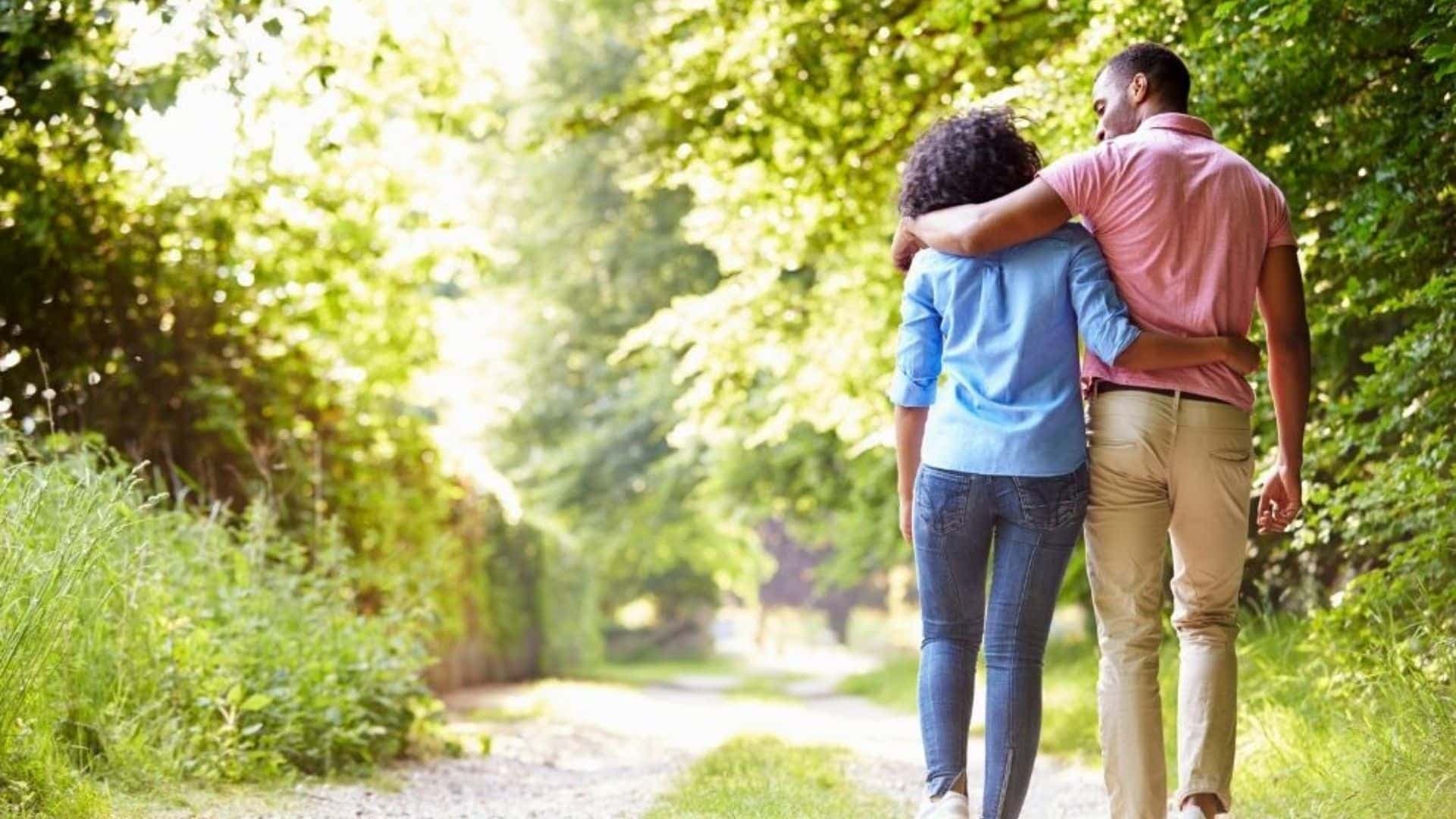 Back view of a man and woman walking together down a nature trail