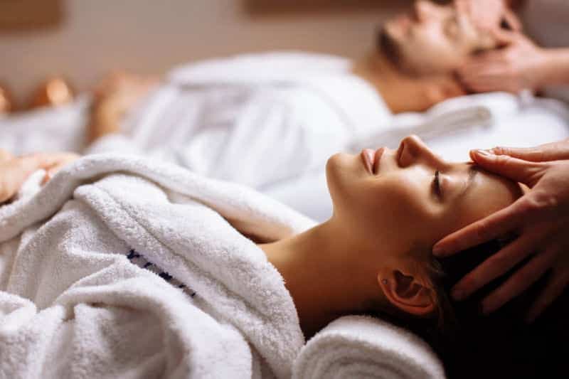 a woman receiving a massage with her partner getting the same massage in the background