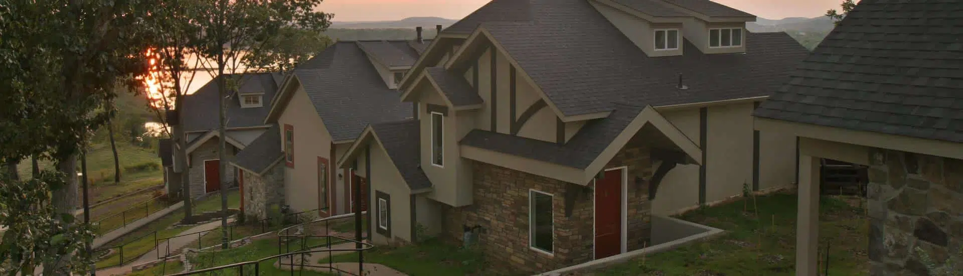 Exterior view of the property with multiple cottages next to each other on a hill with the river and sunsetting in the background