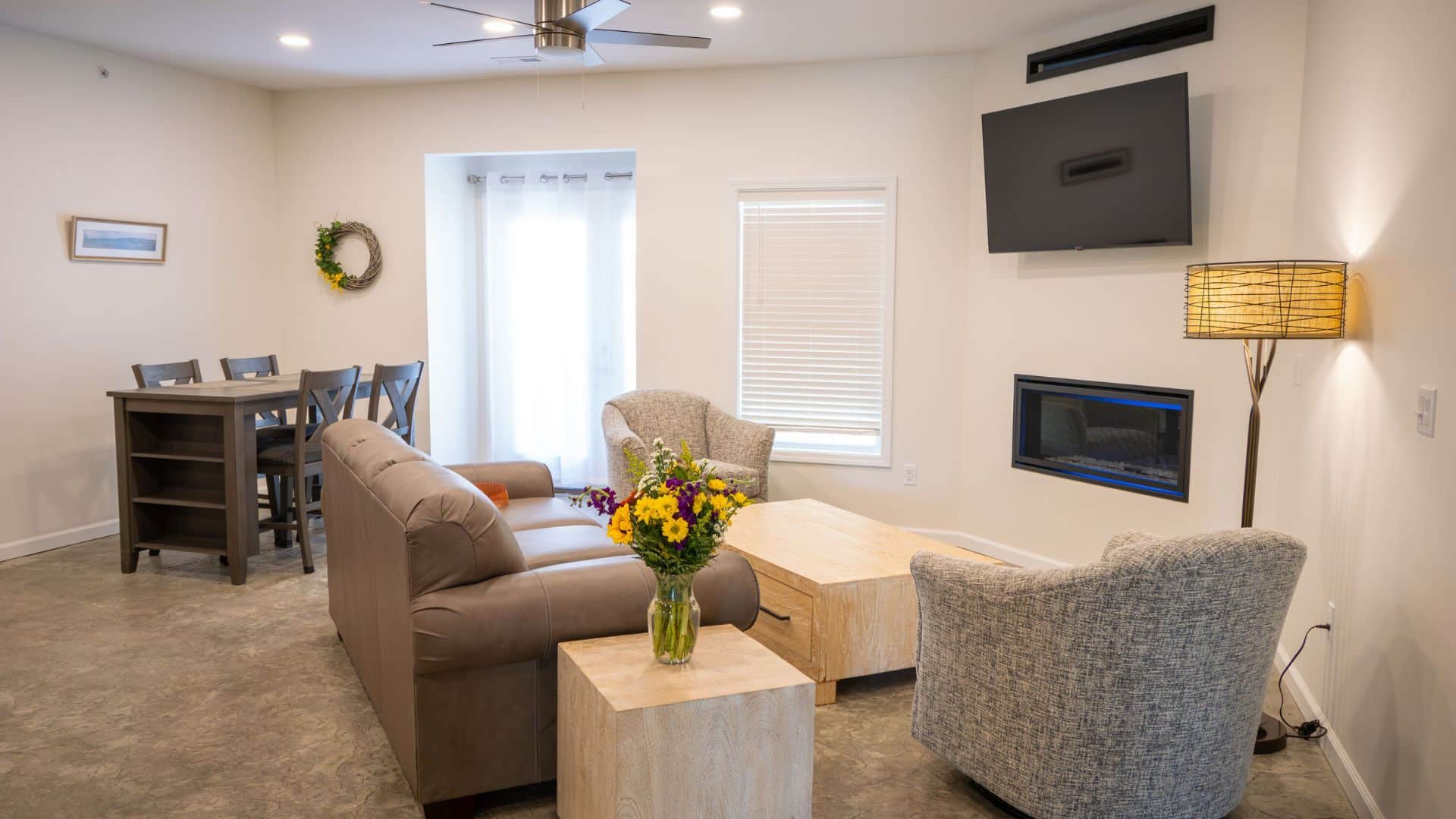 Living Room and dining room combo. Couch facing flat tv on wall with other chairs and tables with fireplace.